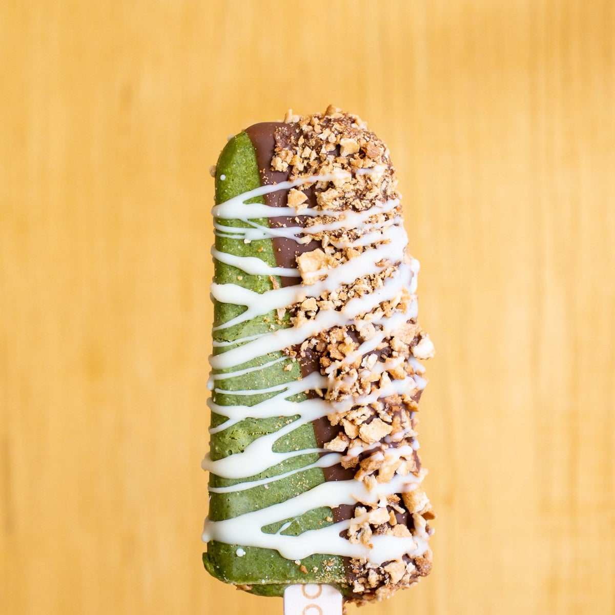 Green Tea Crunch gelato pop dipped in milk chocolate with crushed nuts